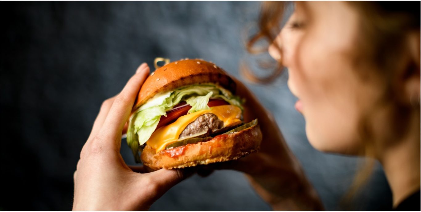 Homemade Burger Eine Person hält einen großen Hamburger mit Salat, Käse und Tomaten.